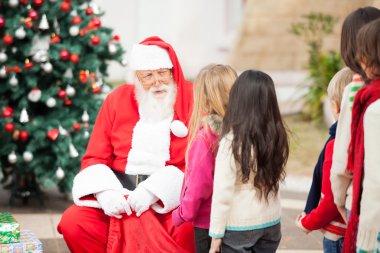 Noel Baba bir sırada duran çocuk bakarak