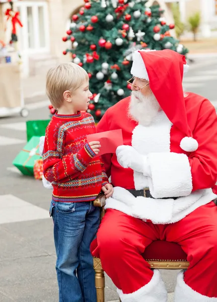 Мальчик передал список желаний Санта-Клаусу — стоковое фото