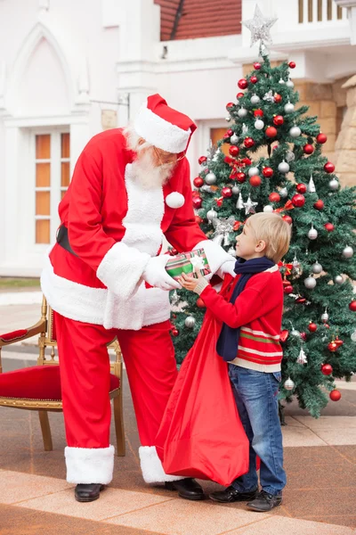 Weihnachtsmann beschenkt Jungen — Stockfoto