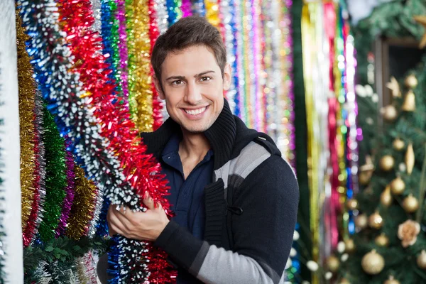 Young Man Choosing Tinsels At Store — Stock Photo, Image