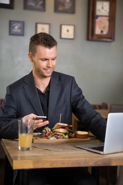 Zakenman met behulp van laptop terwijl het hebben van voedsel in restaurant — Stockfoto