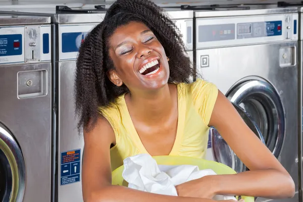 Ung kvinna med kläder korg på laundromat — Stockfoto