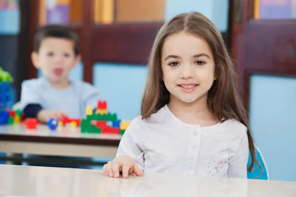 Meisje met vriend in achtergrond bij voorschoolse — Stockfoto