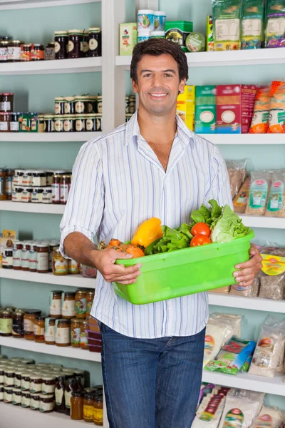 Man med korg med grönsaker i stormarknad — Stockfoto