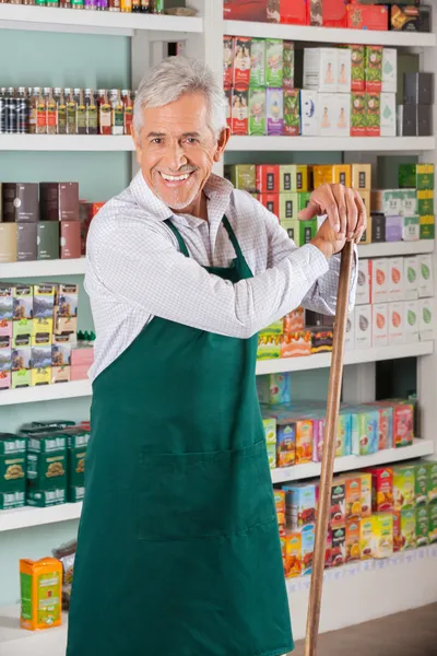 Senior mannelijke eigenaar permanent tegen schappen in de supermarkt — Stockfoto