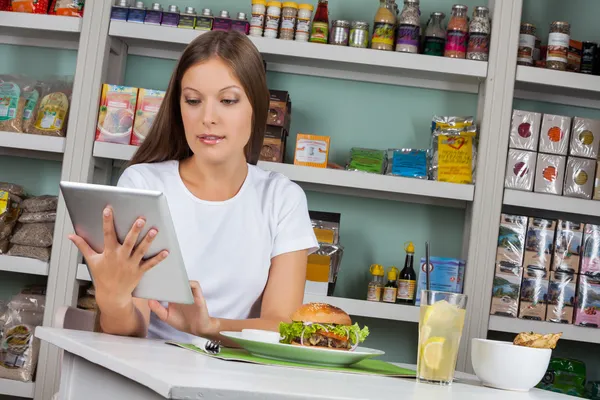 Frau nimmt Tablette beim Imbiss im Supermarkt — Stockfoto