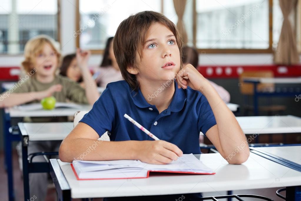 Boy Looking Up While Writing At Desk