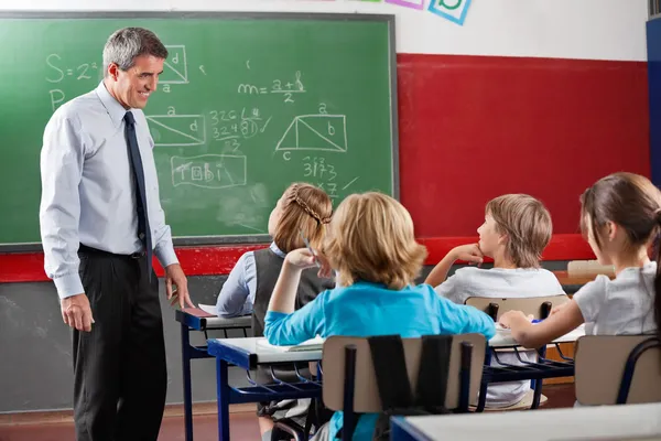 Insegnante guardando gli studenti seduti in aula — Foto Stock