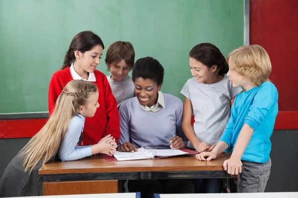 Lehrerin unterrichtet Schüler am Schreibtisch — Stockfoto