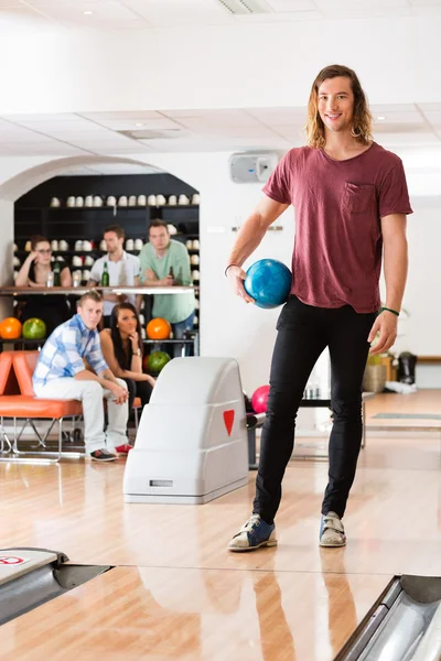 Jonge man houden bal op bowlingclub — Stockfoto
