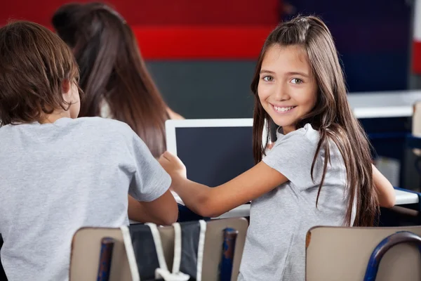 Écolière tenant tablette numérique au bureau dans la salle de classe — Photo