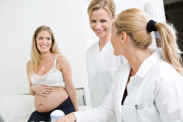 Médecins regardant les uns les autres avec une femme enceinte en clinique — Photo