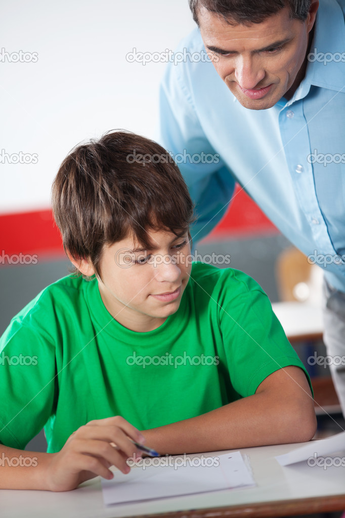 Mature Professor Assisting Teenage Boy At Desk