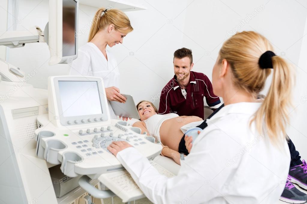 Doctor Showing Digital Tablet To Expectant Couple