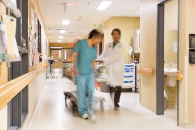 Doktor ve hemşire hastane koridorda sedye çekerek