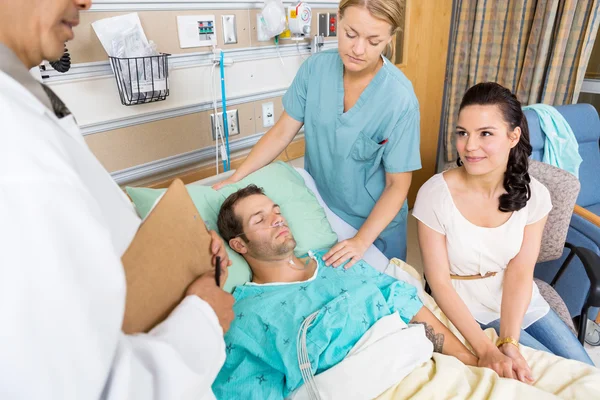 Mujer mirando al doctor mientras sostiene la mano del hombre — Foto de Stock