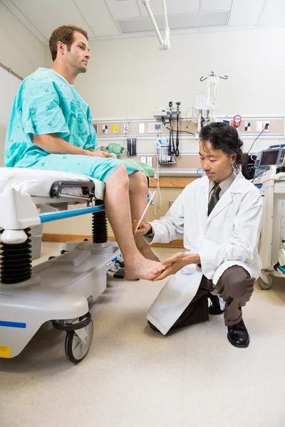 Médico examinando el reflejo del paciente masculino — Foto de Stock