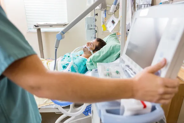 Botón del monitor de presión de enfermera con paciente acostado en la cama — Foto de Stock