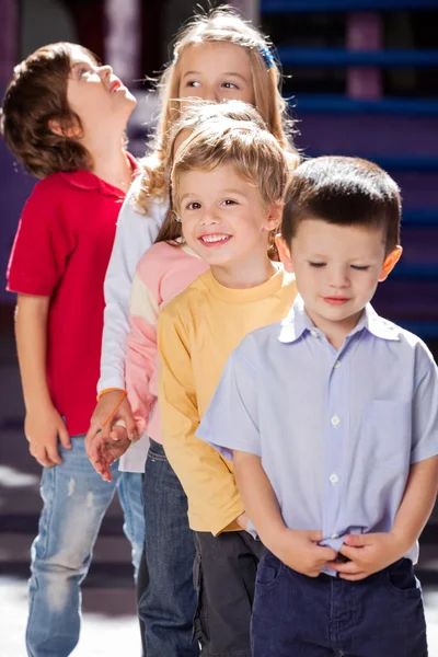 Jongen permanent met vrienden in een rij op de kleuterschool — Stockfoto