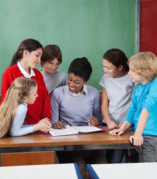 Professoressa che insegna agli studenti alla scrivania — Foto Stock