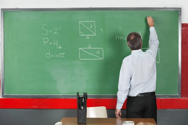 Professora masculina escrevendo no Greenboard na sala de aula — Fotografia de Stock