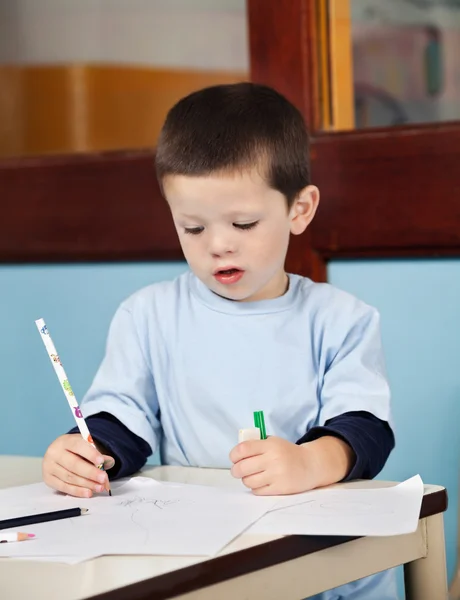 Garçon avec crayon dessin sur papier dans la salle de classe — Photo