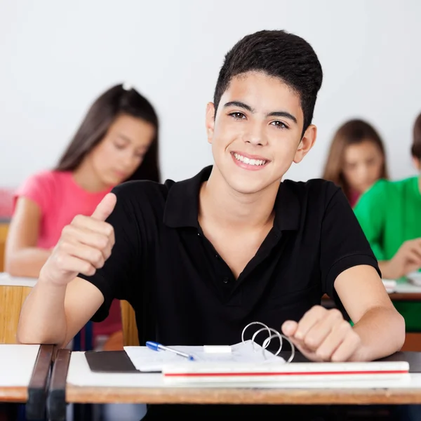 Adolescent écolier gestuelle pouces haut dans salle de classe — Photo