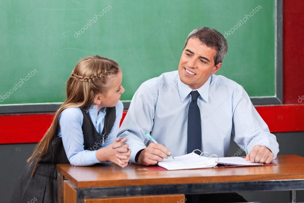 Male Teacher Looking At Schoolgirl In Classroom Stock Photo Male Teacher Looking At Schoolgirl In Classroom Stock Photo