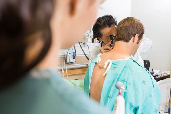 Läkare med otoskop för att undersöka patientens öra — Stockfoto