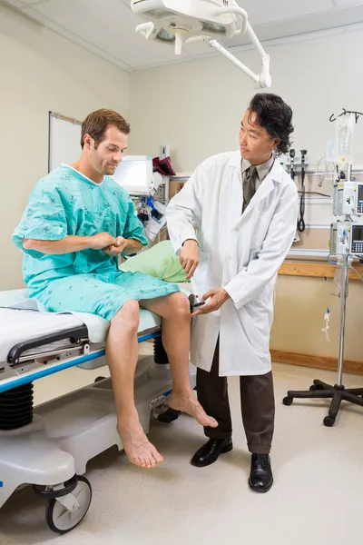 Neuroloog onderzoeken patiënt knie met hamer in ziekenhuis — Stockfoto