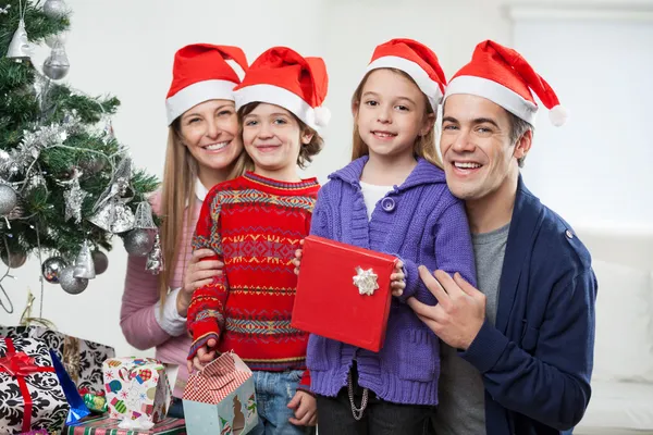 Familj i santa hattar med julklapp — Stockfoto