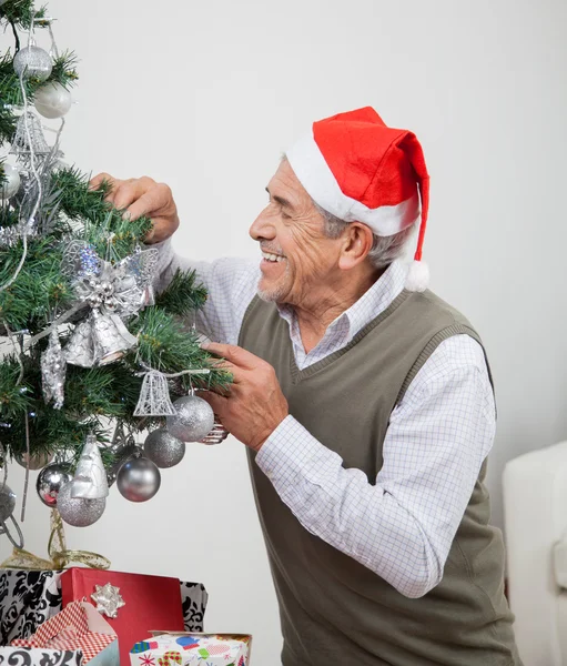 Muž nosí klobouk santa zdobení vánočního stromu — Stock fotografie