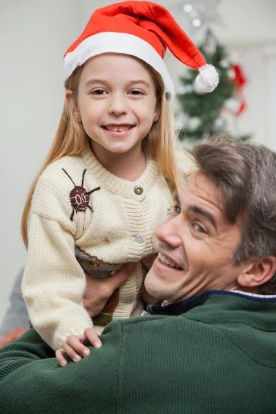 Mädchen mit Weihnachtsmütze wird vom Vater getragen — Stockfoto