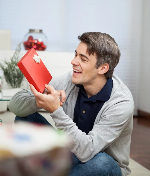 Улыбающийся смотрит на рождественский подарок — стоковое фото
