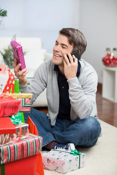 Man med julklapp samtidigt svarande mobiltelefon — Stockfoto