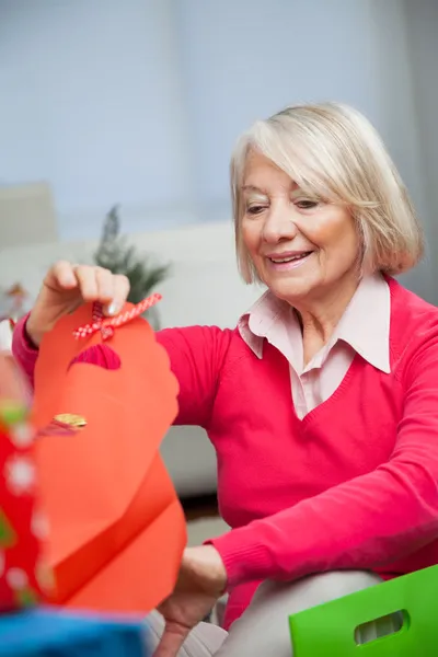 Lächelnde Seniorin schaut zu Hause in Tasche — Stockfoto