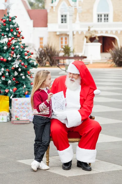 Chica mostrando lista de deseos a Santa Claus — Foto de Stock