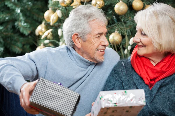 Pareja mayor con regalos en la tienda de Navidad — Foto de Stock