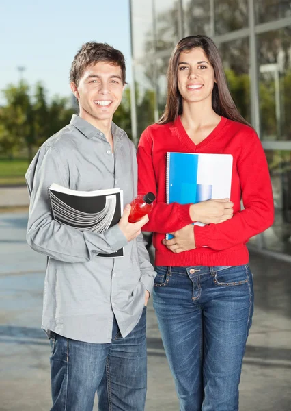 Estudiantes sosteniendo libros mientras están en la universidad — Foto de Stock