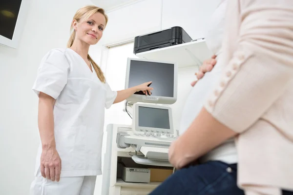 Ginecólogo mostrando ultrasonido escáner a mujer embarazada —  Fotos de Stock