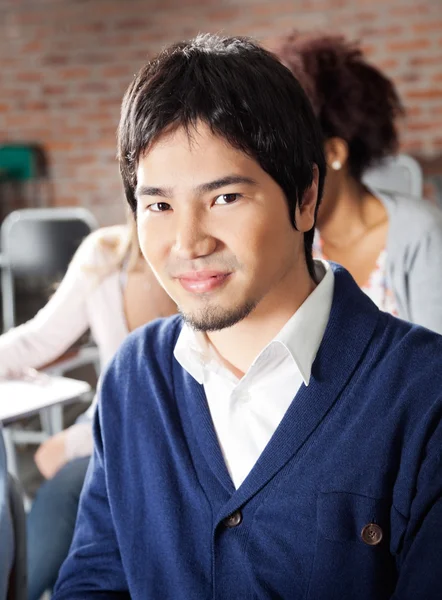 Studente seduto con compagni di classe in background in aula — Foto Stock