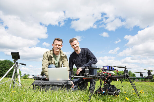 Men Using Laptop Next To UAV