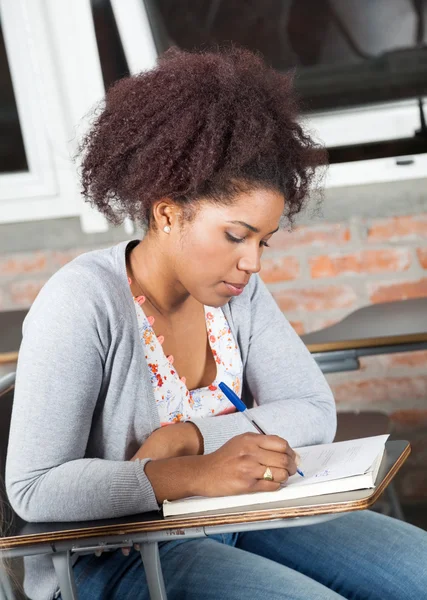 Student schriftelijk examen op Bureau in klas Stockfoto