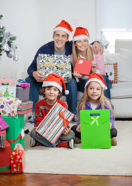 Familj i santa hattar håller julklappar — Stockfoto