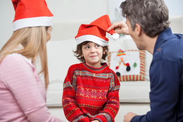 Os pais olhando para o filho vestindo chapéu de Santa — Fotografia de Stock