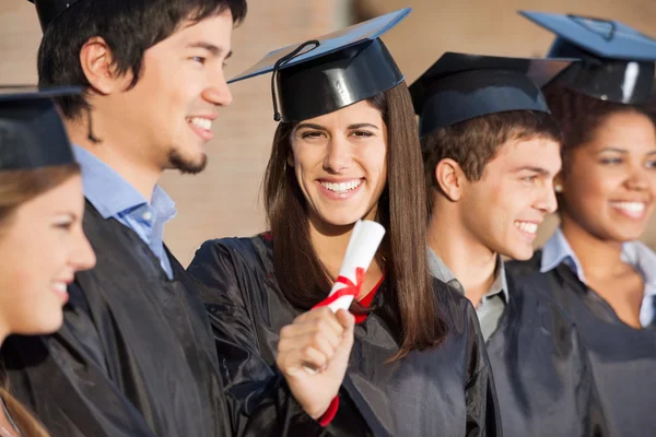 Estudiante graduado con diploma mientras está de pie con sus amigos en —  Fotos de Stock
