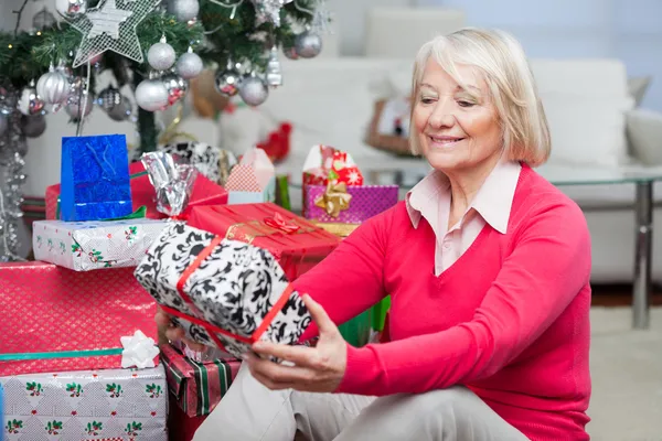 Seniorin schaut sich Weihnachtsgeschenk an — Stockfoto