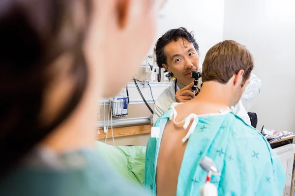 Doktor s upevnĕní zkoumání ucha pacienta v nemocnici — Stock fotografie