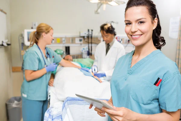 Verpleegster met digitale tablet terwijl arts en collega operationele p — Stockfoto