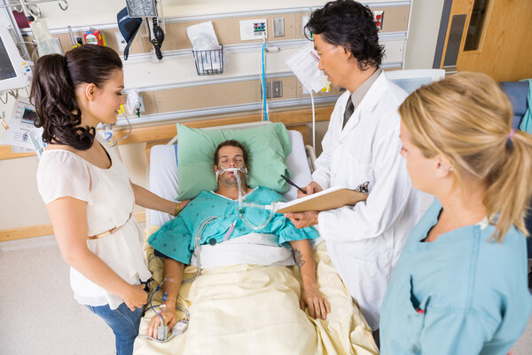 Doctor And Nurse With Woman Looking At Critical Patient